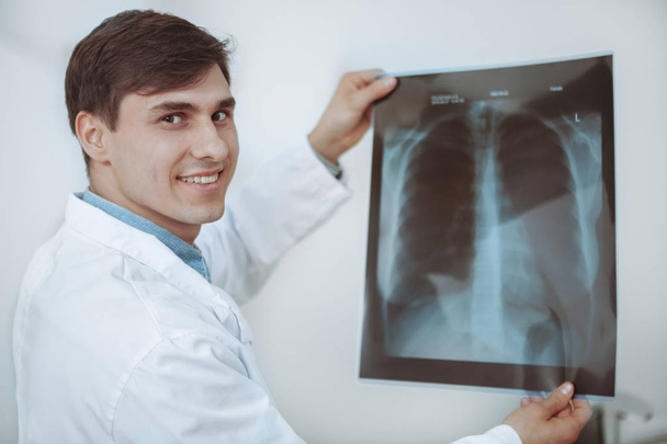 Mannelijke arts onderzoekt x-ray scan op zijn kantoor - Foto, afbeelding
