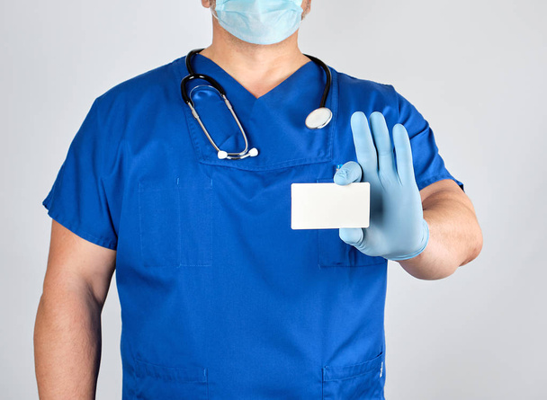 médico en guantes de látex estériles y uniforme azul sostiene un blanco wh
 - Foto, imagen