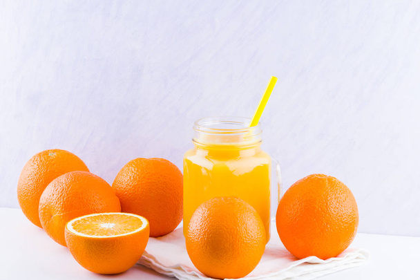 Frutas de laranja e suco no fundo branco. Frutas cítricas para fazer suco com espremedor manual. Laranjas em guardanapo branco. Frasco Mason com suco de laranja
 - Foto, Imagem