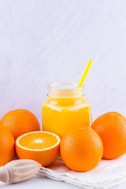 Orange fruits and juice on white background. Citrus fruit for making juice with manual juicer. Oranges on white napkin. Mason jar with orange juice - Foto, Imagem