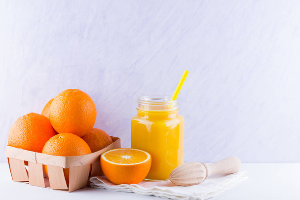 Orange fruits and juice on white background. Citrus fruit for making juice with manual juicer. Oranges in wooden box on white napkin. Mason jar with orange juice - Foto, afbeelding