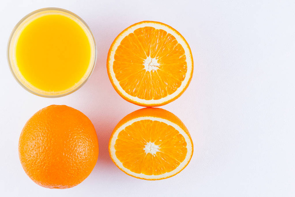 Orange fruits with juice, concept. Orange juice and halves of oranges on white background. Citrus for making juice. Whole and squeezed oranges and glass of juice - Fotografie, Obrázek
