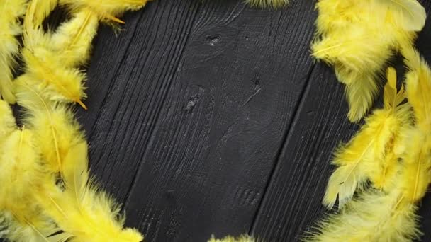Colorful decorative Easter feather wreath on black wooden table background - Footage, Video