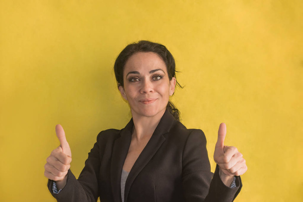 Brunette Business vrouw over geïsoleerde achtergrond maken Happy thumbs up - Foto, afbeelding