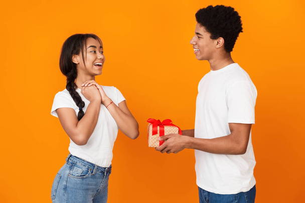 Teen guy giving his girlfriend gift over background - Foto, afbeelding