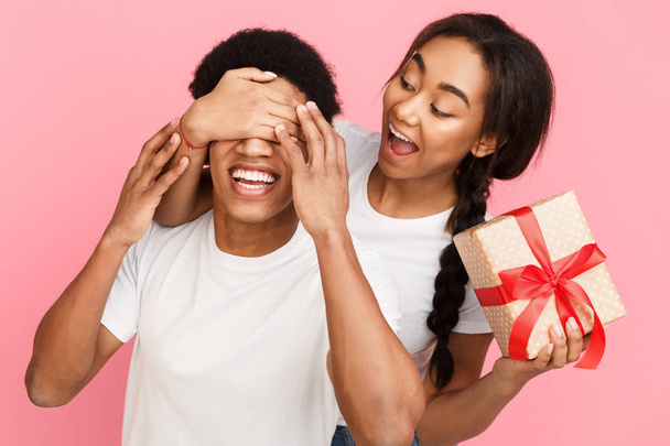 Chica cubriendo ojos de novio y dándole regalo
 - Foto, Imagen