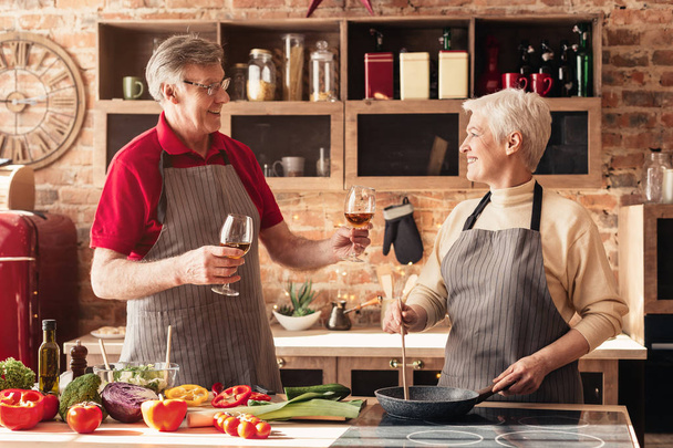 Affectionate retired couple drinking wine in kitchen - Fotografie, Obrázek