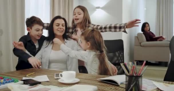 Velmi charismatická dospělá matka se svými třemi dětmi si dělá přátelskou týmovou spolupráci, která se navzájem uhání a tráví v moderním obývacím pokoji dobrou dobu.. - Záběry, video