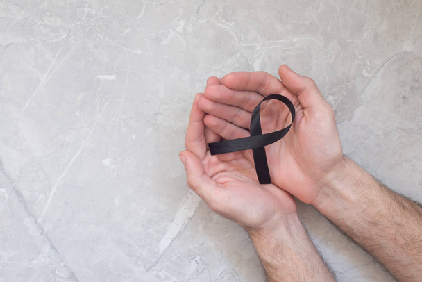 Człowiek trzyma Wstążkę czarnego raka, symbol czerniaka. Koncepcja zdrowia i medycyny.  - Zdjęcie, obraz