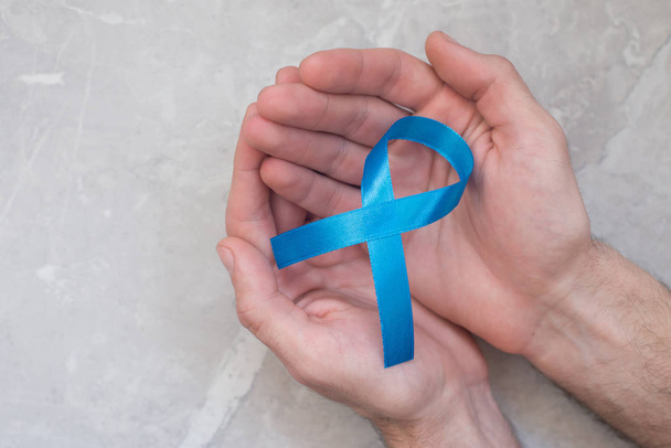 Man holding blue cancer ribbon, symbol of prostate cancer. Concept of health and medicine. - Foto, imagen