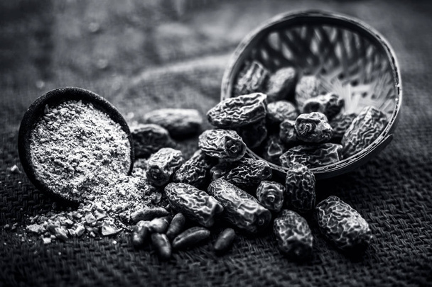Close up dried dates of kharek or Phoenix dactylifera in a fruit basket on brown surface. Black and white - Foto, Imagen