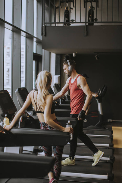 Egzersiz sonrası spor salonunda genç kadın ve kişisel erkek eğitmen dinlenme - Fotoğraf, Görsel