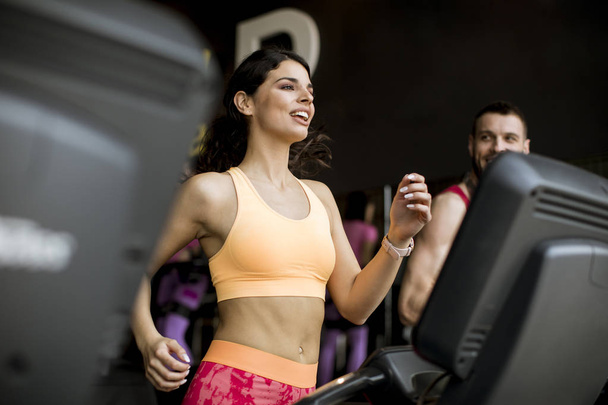 Young couple running on treadmills in modern gym - Photo, Image