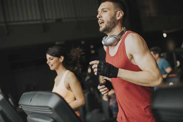 Young couple running on treadmills in modern gym - Fotó, kép
