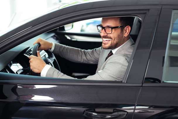 Businessman is sitting in the car in the showroom - Foto, imagen