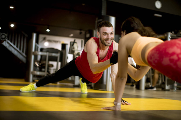 Εφαρμογή αθλητικός άνθρωπος και γυναίκα κάνει άσκηση πυρήνα σανίδα στο γυμναστήριο - Φωτογραφία, εικόνα