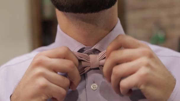 新郎は、理髪店の背景に蝶ネクタイを調整します。花嫁に行くための準備 - 映像、動画