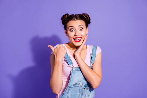Close up photo beautiful amazing she her lady two buns shocked cool show thumb finger sale discount shopping  wear casual t-shirt jeans denim overalls clothes isolated purple violet background - Φωτογραφία, εικόνα