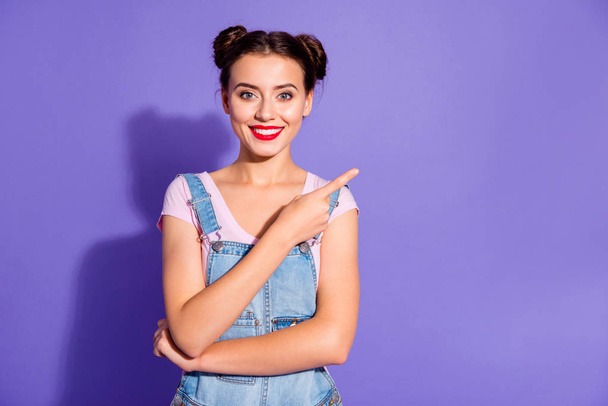 Close up photo beautiful amazing she her lady buns show indicate direct index finger empty space new product wear casual t-shirt jeans denim overalls clothes isolated purple violet background - Fotografie, Obrázek