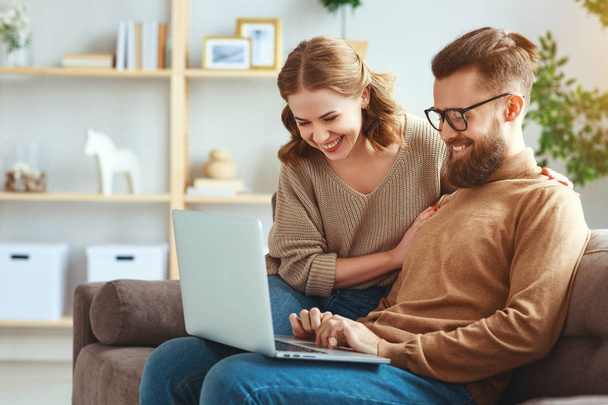 casal feliz com computador portátil em casa
  - Foto, Imagem
