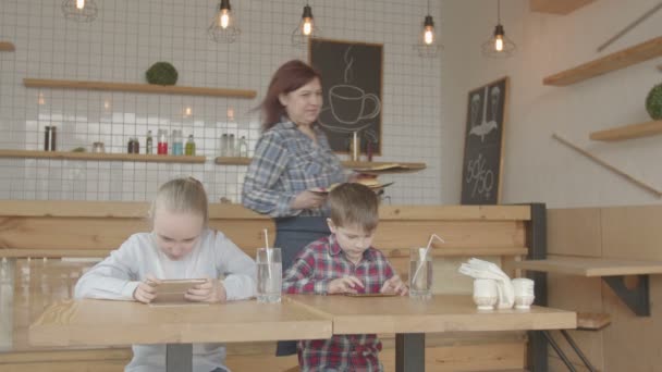 Kids with phones rejoicing fast food meal in cafe - Materiał filmowy, wideo