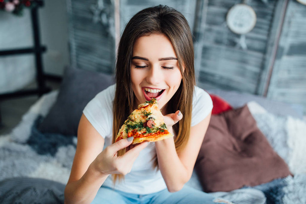 Beautiful young woman eating pizza, focus on foreground - Foto, afbeelding