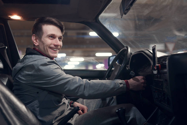 Фотографія з боку щасливого чоловіка, дивлячись на камеру, що сидить в машині
 - Фото, зображення
