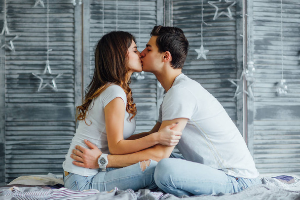 young beautiful couple kissing in bed at home, focus on foreground - Foto, afbeelding