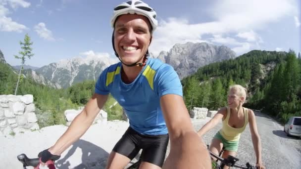 Αργή κίνηση selfie χαρούμενο σπορ ζευγάρι Ποδηλασία πάνω βουνό δρόμο σε μια όμορφη καλοκαιρινή μέρα. Αθλητικό αγόρι και κορίτσι απολαμβάνοντας την ύπαιθρο ιππασία ποδήλατα στα βουνά. Ενεργοί νεόνυμφοι στο μήνα του μέλιτος - Πλάνα, βίντεο