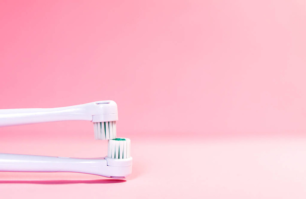Dos cepillos de dientes eléctricos sobre un fondo rosa claro suave
 - Foto, Imagen