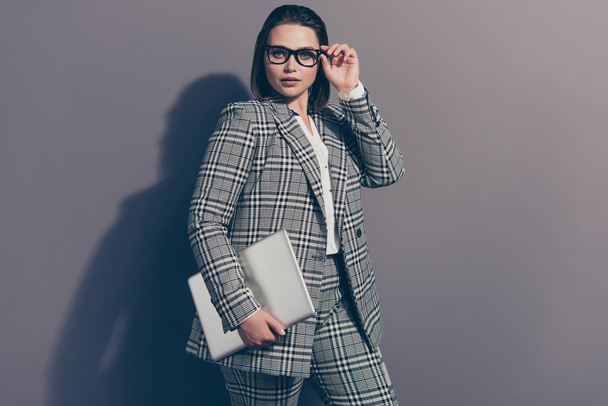 Portrait of graceful pretty intelligent attractive glad nice lovely thoughtful she her lady wearing classic plaid white jacket pants holding netbook in arm palm isolated grey background - Fotografie, Obrázek