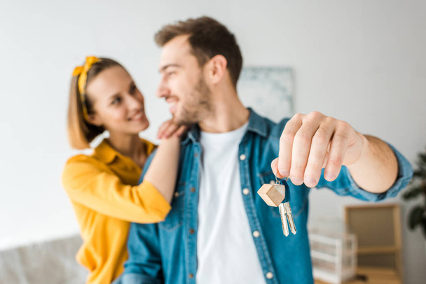 Selective focus of happy couple with keys at home - Foto, afbeelding