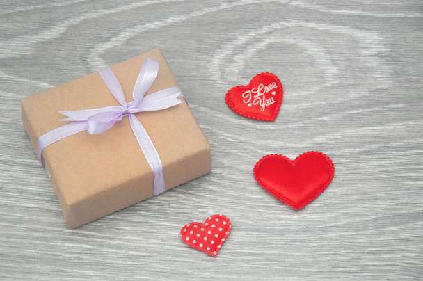 Pudełko z czerwonymi serduszkami na szarym drewnianym tle. Karta okolicznościową na Walentynki. - Zdjęcie, obraz