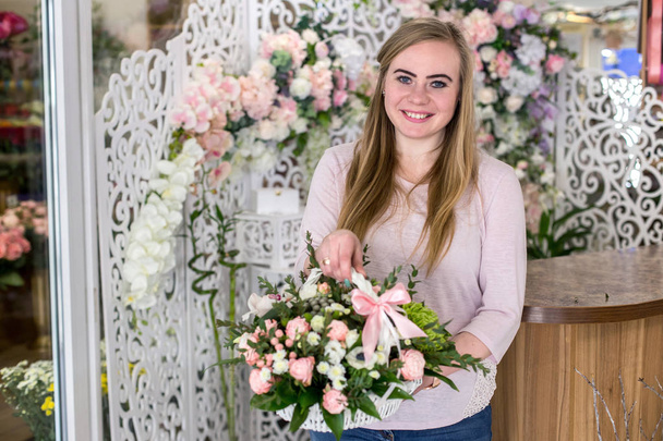 Smiling young florist woman holding a beautiful bouquet of roses - Photo, Image