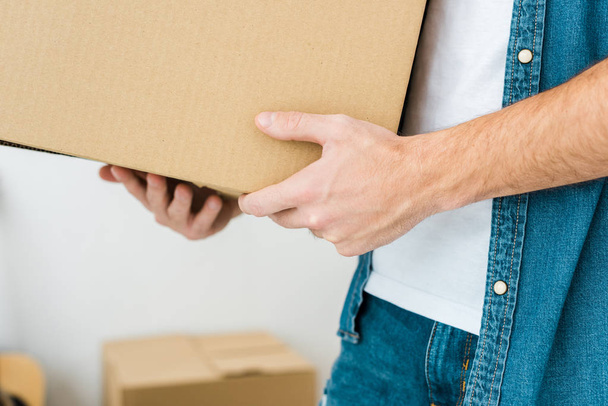 partial view of man in denim shirt holding cardboard box - Photo, Image