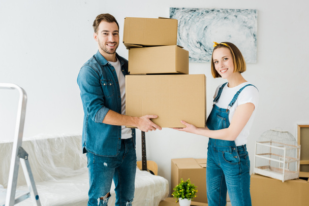 Happy couple holding cardboard boxes and looking at camera - Photo, Image