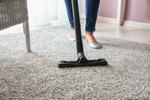 Woman hoovering carpet with vacuum cleaner - Photo, Image