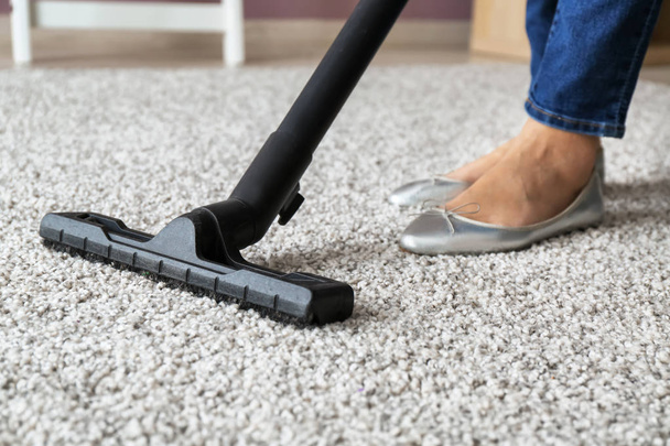 Woman hoovering carpet with vacuum cleaner - Zdjęcie, obraz