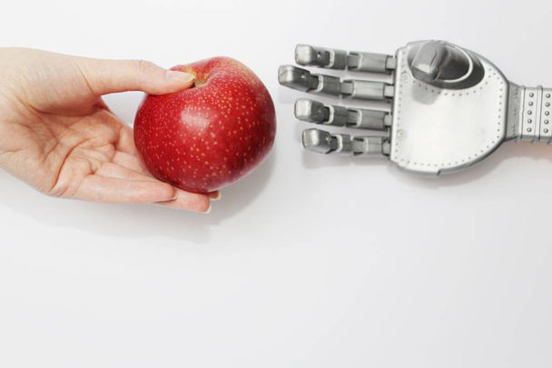 The hand of a real man gives the robot a red apple. - Φωτογραφία, εικόνα
