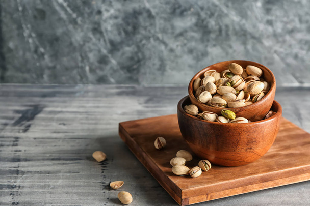 Bowls with tasty pistachio nuts on grey table - Valokuva, kuva