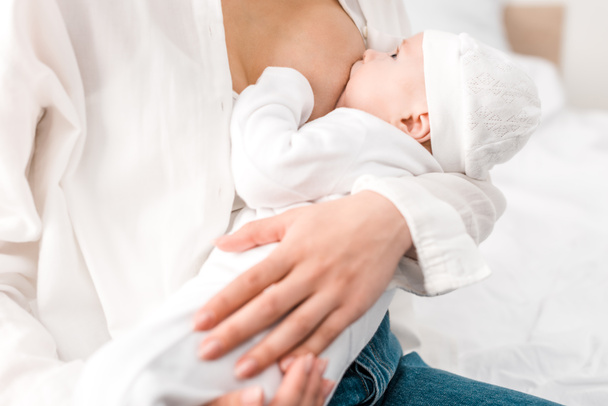 Cropped view of mother breastfeeding baby at home - Foto, imagen