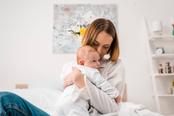 Happy mother in white shirt holding baby at home - Zdjęcie, obraz