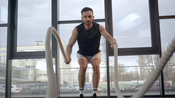 Вид спереди концентрированного спортсмена, делающего упражнения с веревками в тренажерном зале
 - Кадры, видео