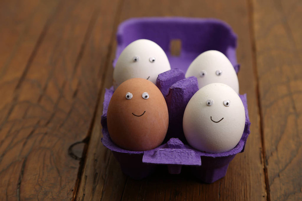 Αυγά κοτόπουλου με ζωγραφισμένα πρόσωπα είναι στο κουτί - Φωτογραφία, εικόνα