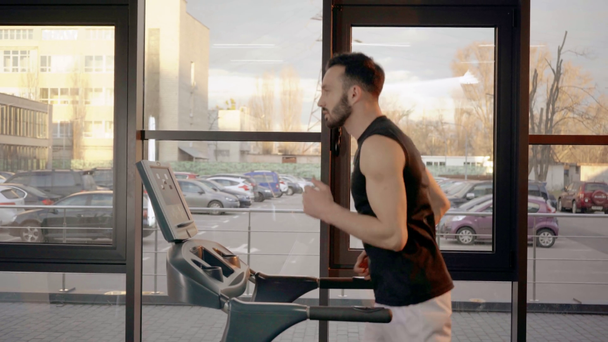 Side view of sportsman in white shorts running on treadmill - Video, Çekim