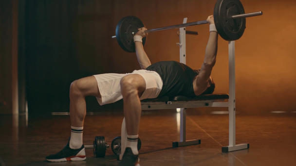 Powerlifter en pantalones cortos blancos y zapatillas de deporte haciendo press de banca
 - Metraje, vídeo