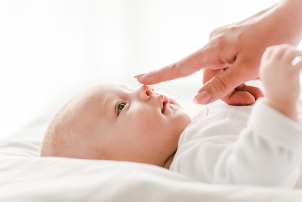 bijgesneden beeld van moeder zachtjes aanraken baby in de slaapkamer - Foto, afbeelding