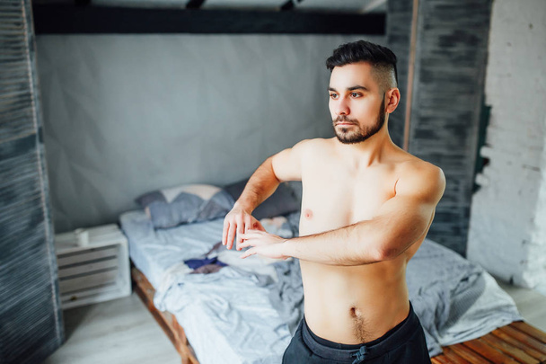 Handsome bearded man doing abdominals exercises near window at home  - Foto, Bild