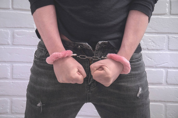 sexy guy standing in handcuffs against a white loft. - Photo, Image