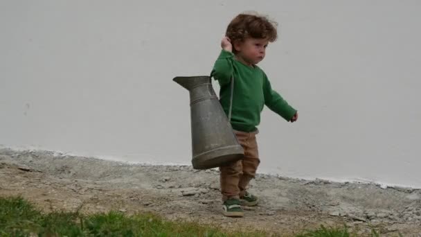 grappige jonge jongen met groene trui spelen met oude werper buitenshuis - Video